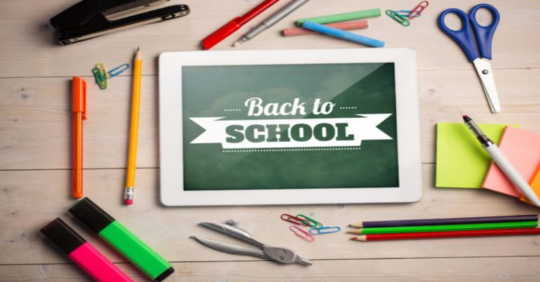 back to school cybersecurity written on a tablet on a desk top with school supplies
