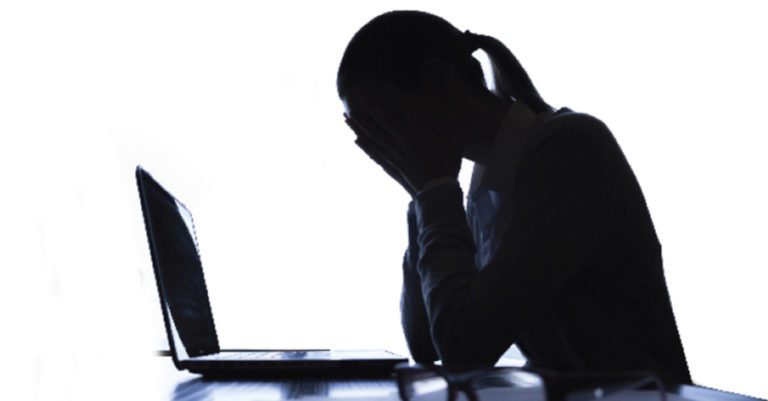 insider threats like human error represented by the silhouette of a woman with her head in her hands in front of a laptop.