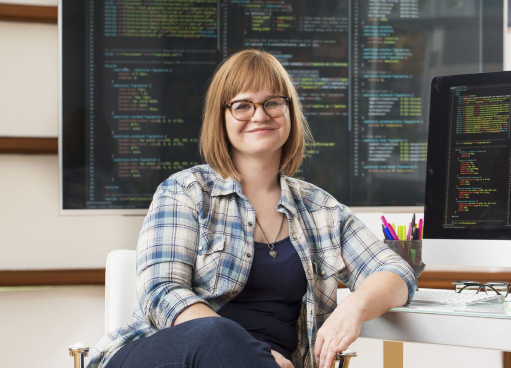 a white woman smiling at a desk with data readouts behind her in a Managed SOC