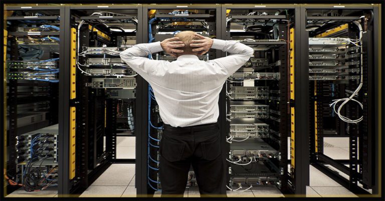 a caucasian man in business attire puts his hands on his head in shock in front of a server rack