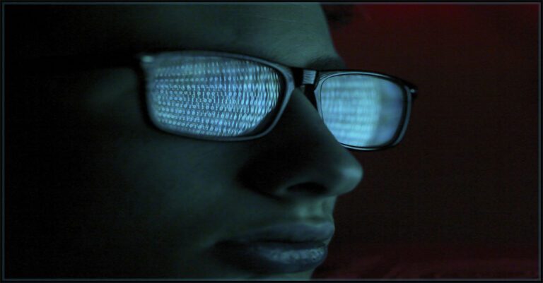 dark web user with binary code reflected in a pair of eyeglasses