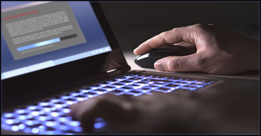 a shadowy image of a caucasian male hand moving a mouse while downloading data using a laptop