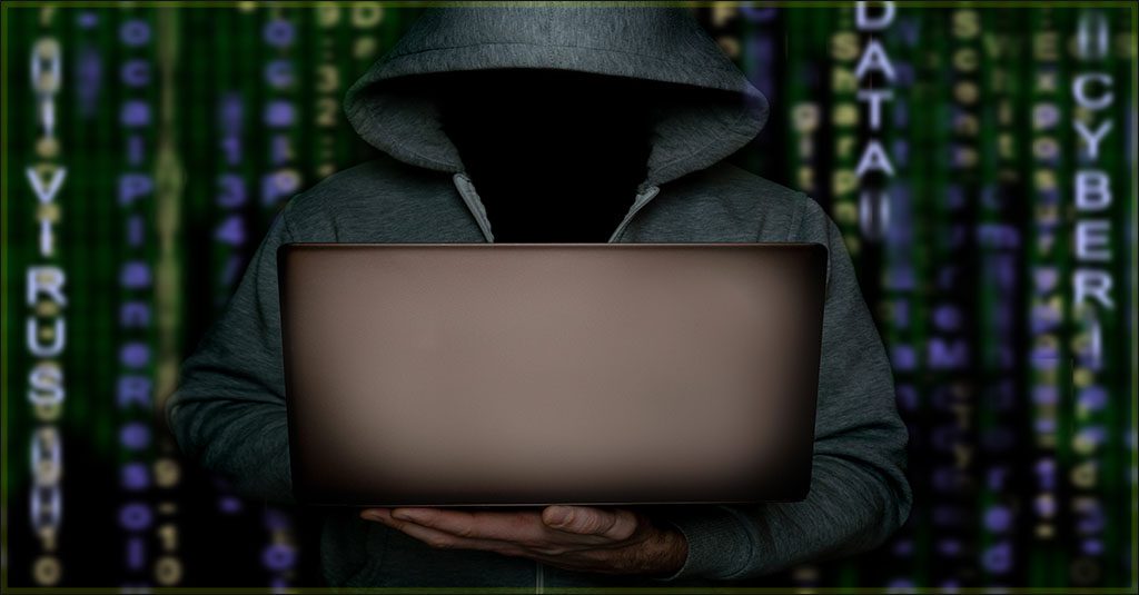 a shadowy image of a hacker in a hoodie standing in front of a screen of vertical binary code